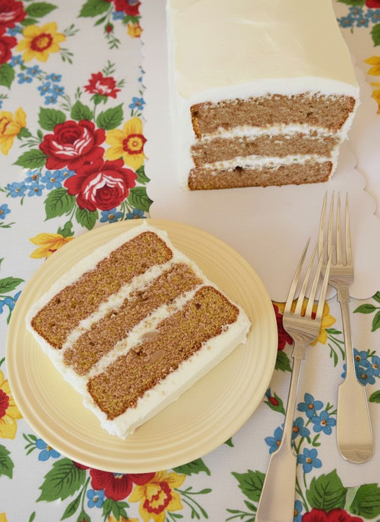 Two slices of layered cake on a floral tablecloth with a knife and fork.