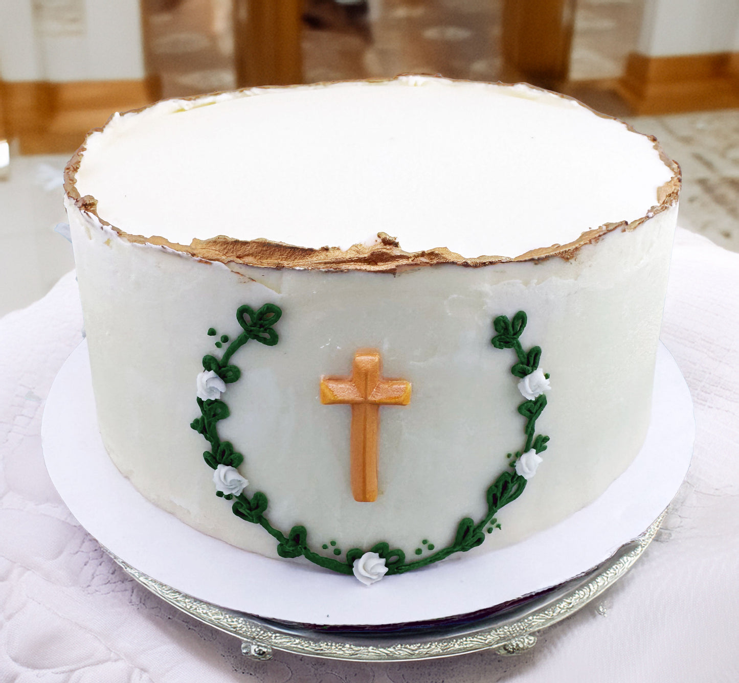 White cake with a cross and green decorations on a white plate.