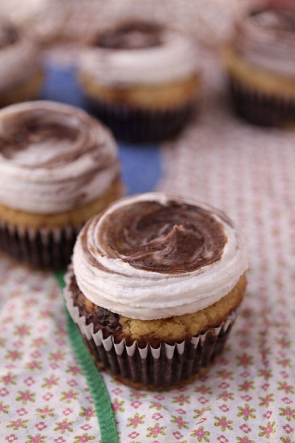 Cupcakes with chocolate and vanilla frosting on a floral tablecloth