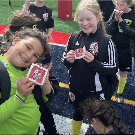 Children holding cookies with images imprinted on them on a sports field
