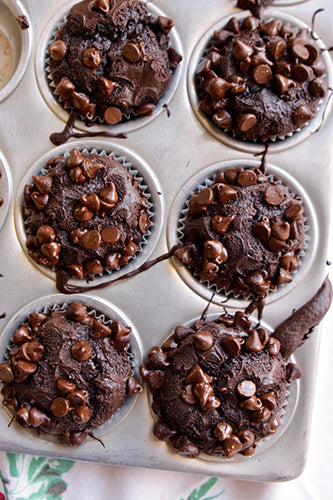 Chocolate muffins with chocolate chips in a muffin tin.