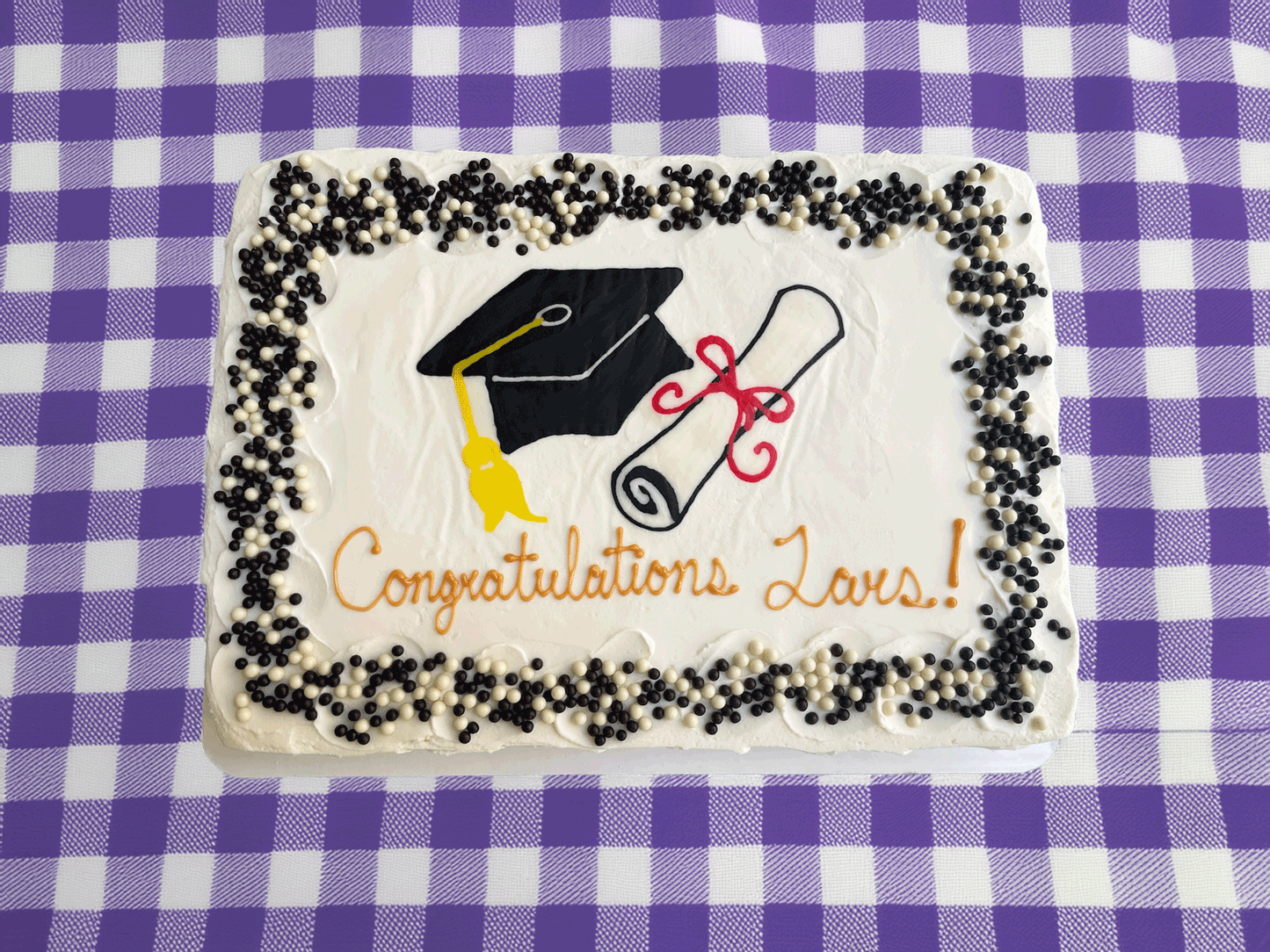 Photo of a rectangular cake with a hand-drawn image of a graduatino cap and scroll.