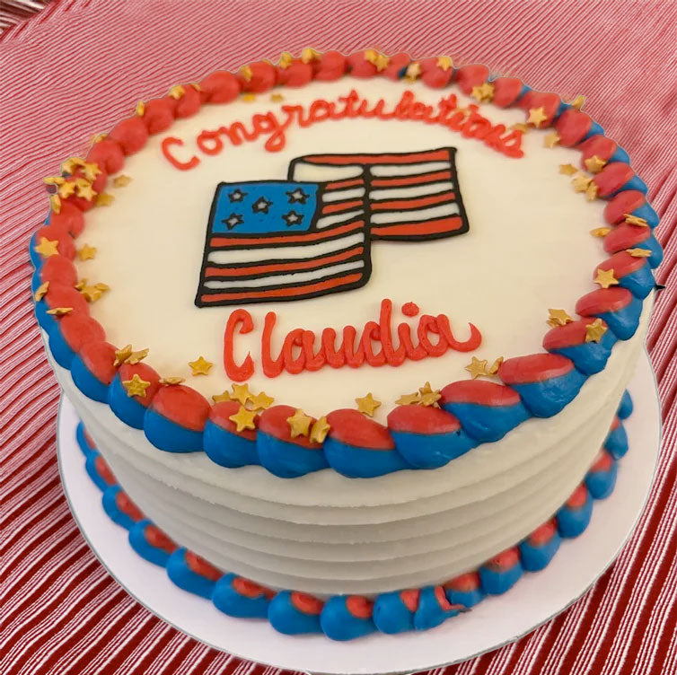 Cake with 'Congratulations Claudia' text and American flag design on a red and white striped background