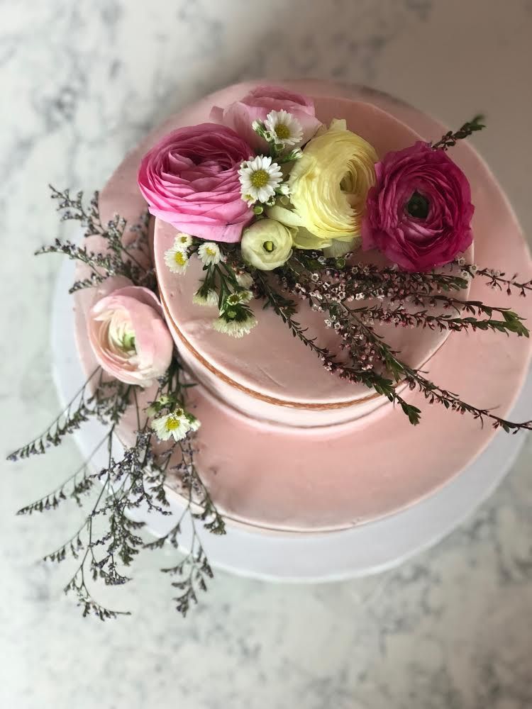 Pink cake with floral decorations on a marble surface