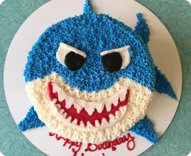 Baby Shark birthday cake with blue frosting, white and red details, and 'Happy Birthday Alex!' written in red icing.
