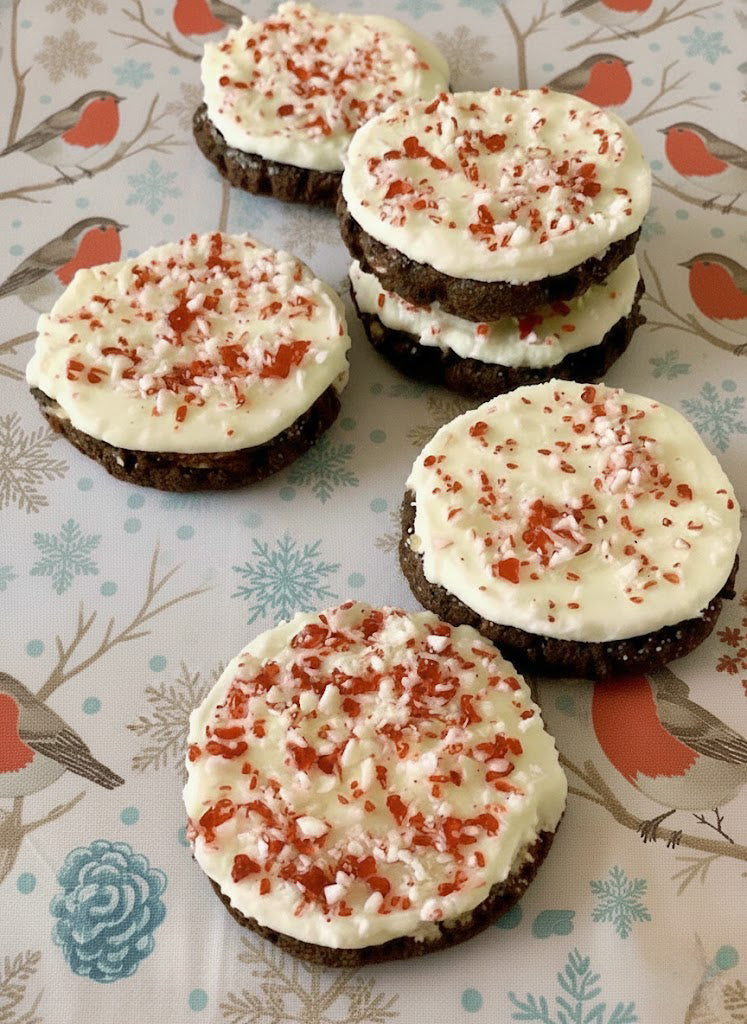 Chocolate cookies with white frosting and red sprinkles on a patterned background