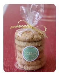 Stack of Billy's Bakery cookies in clear packaging with a green and white 'Billy's Bakery' label and yellow ribbon.
