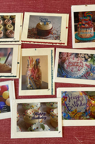 A collection of various greeting cards laid out on a surface, featuring different designs and texts such as 'Happy Birthday'.