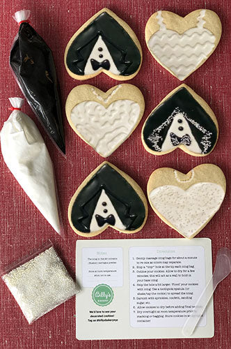 Heart-shaped wedding cookies decorated as bride and groom attire, alongside piping bags with icing and instructions for a DIY cookie decorating kit.