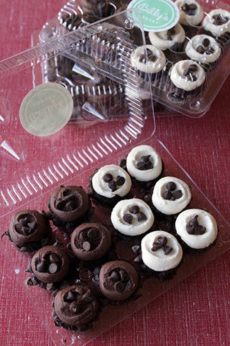 Two clear containers of Billy's Chocolate Chip Cupcakes. Some cupcakes have chocolate frosting, while others have white frosting, both topped with chocolate chips.