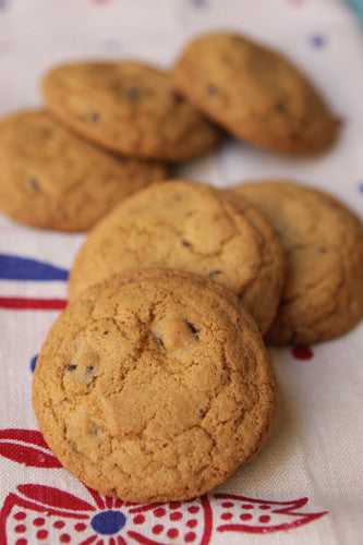 A photo of several gluten-free chocolate chip cookies on a patterned fabric.