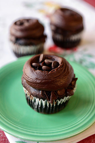 Gluten free vegan chocolate cupcake with chocolate frosting and chocolate chips on a green plate