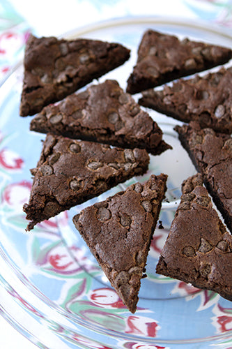 Triangular chocolate chip brownies or skillet cookie slices arranged on a light blue and white patterned plate