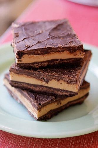 Stack of three Peanut Butter Chocolate Bars on a white plate with a red background