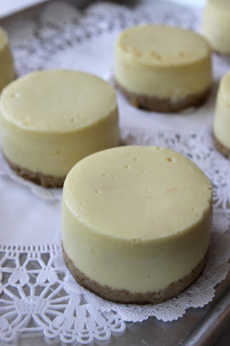 Plain cheesecakes with graham cracker crust on a plate, garnished with a white lace doily.