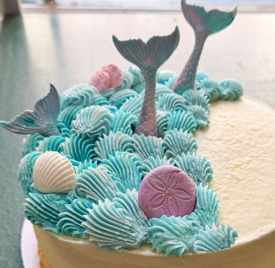 Buttercream cake frosted in white buttercream, with hand-drawn Mexican elements. 