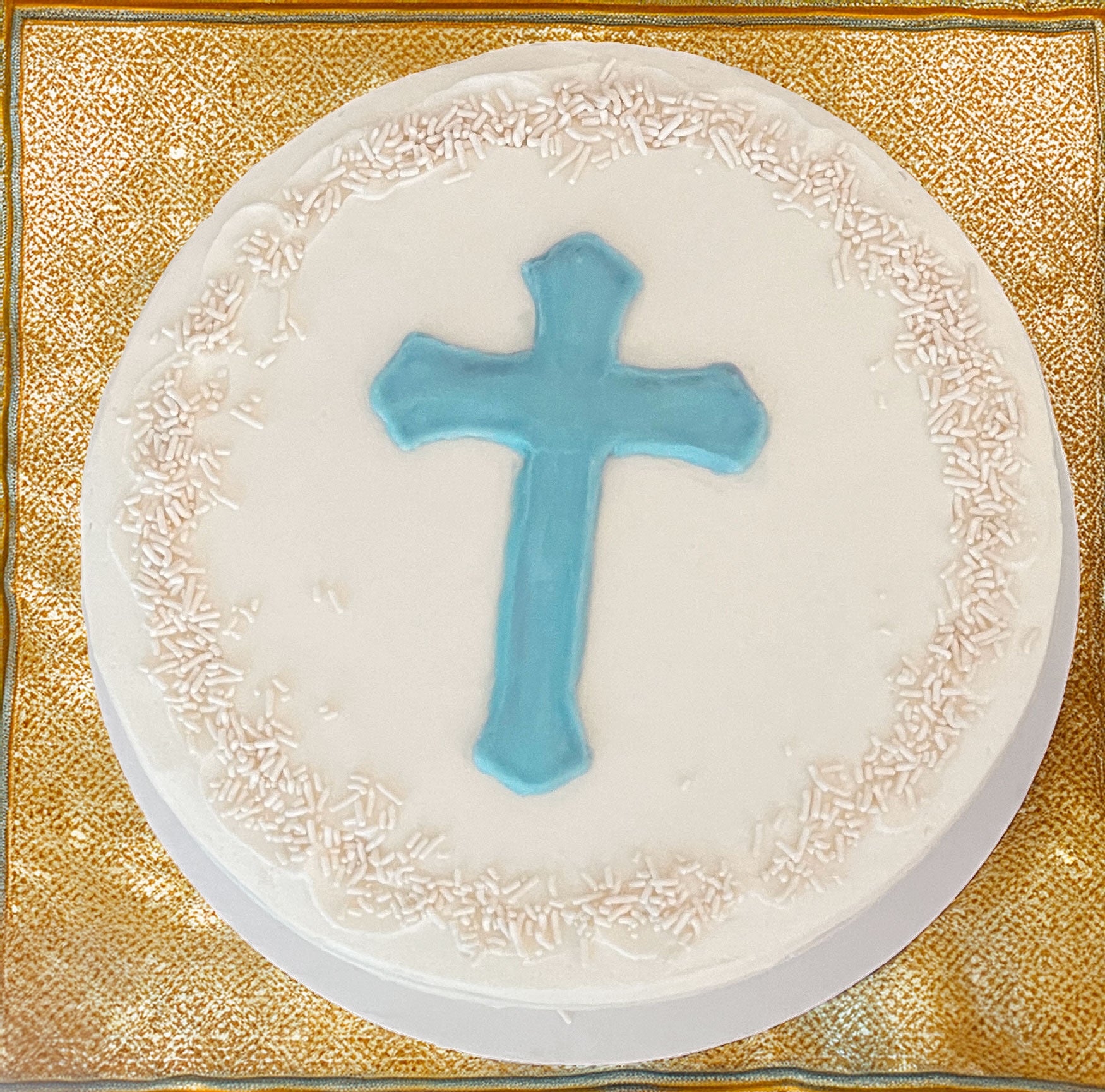 Round white cake with a blue cross on a gold background