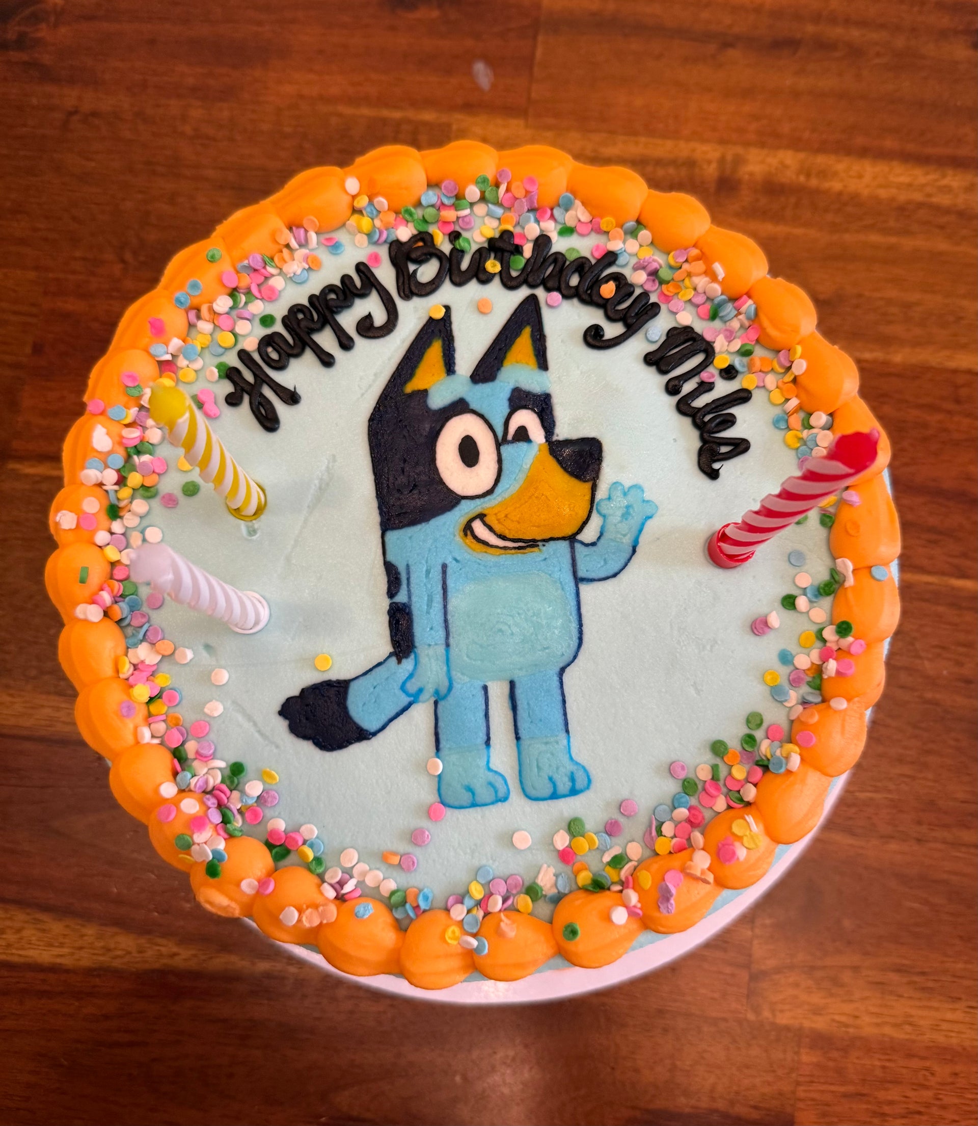 Birthday cake with a cartoon character and 'Happy Birthday' text on a wooden surface