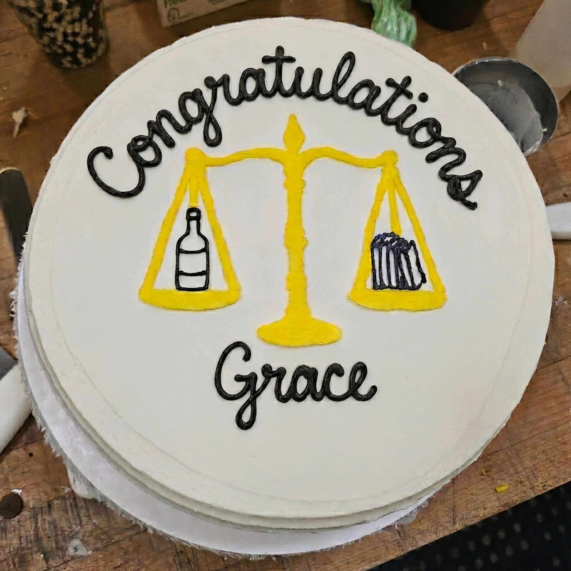 Cake with 'Congratulations Grace' text and scales design on a wooden surface