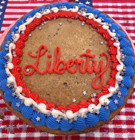 Cookie cake with 'Liberty' decoration on a red, white, and blue checkered tablecloth.