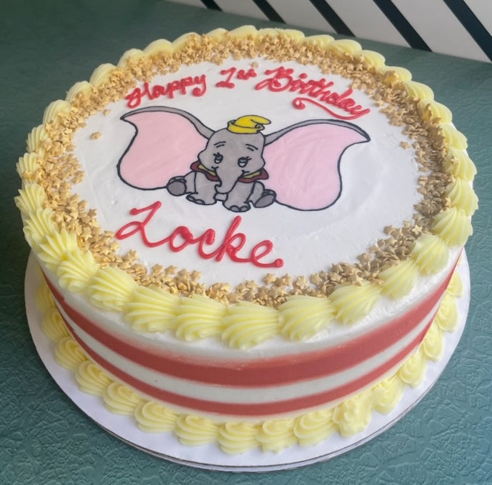 Birthday cake with cartoon elephant and 'Happy 2nd Birthday Locke' text on a green surface
