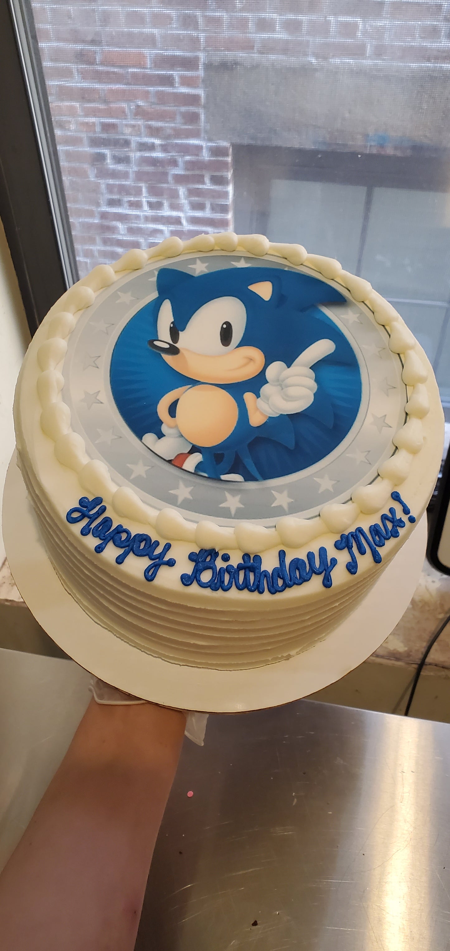 Birthday cake with cartoon character and 'Happy Birthday' text on a windowed surface.
