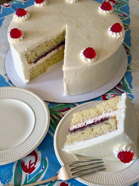 White cake with red berries on a floral tablecloth