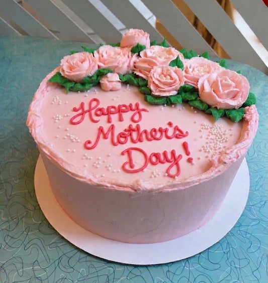 Pink cake with 'Happy Mother's Day!' text and floral decorations on a light blue surface.