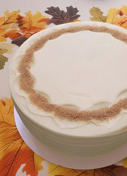 Green cake with brown trim on a decorative leaf-patterned surface