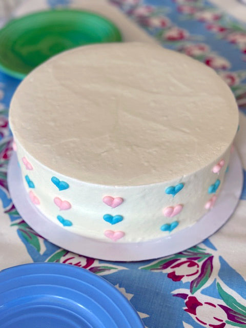 Round cake with colorful heart decorations on a floral tablecloth