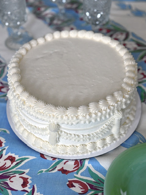 White frosted cake on a patterned tablecloth